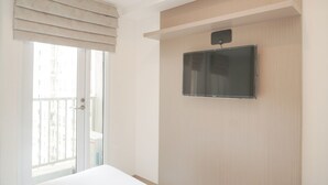 Ein Hotelzimmer mit einem großen Bett, einem an der Wand befestigten Fernseher und einer Glastür zum Balkon.