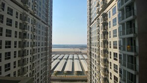 A high-rise building with multiple balconies and a view of a flat landscape in the distance. - Simply Studio At 18Th Floor Tokyo Riverside Pik 2 Apartment (Teluknaga)