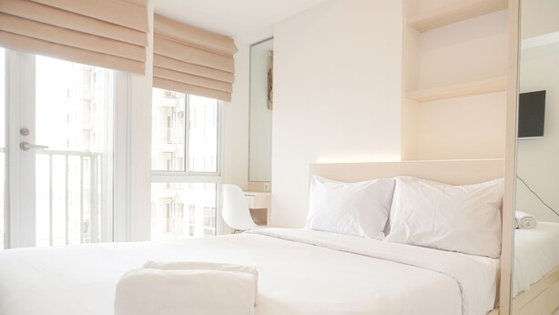 A hotel room with a large bed, a desk, and a window with blinds. - Simply Studio At 18Th Floor Tokyo Riverside Pik 2 Apartment (Teluknaga)