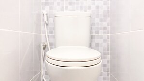 A white toilet with a tiled wall background. - Simply Studio At 18Th Floor Tokyo Riverside Pik 2 Apartment (Teluknaga)