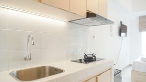 A modern kitchen with a stainless steel sink, a gas stove, and wooden cabinets. - Simply Studio At 18Th Floor Tokyo Riverside Pik 2 Apartment (Teluknaga)