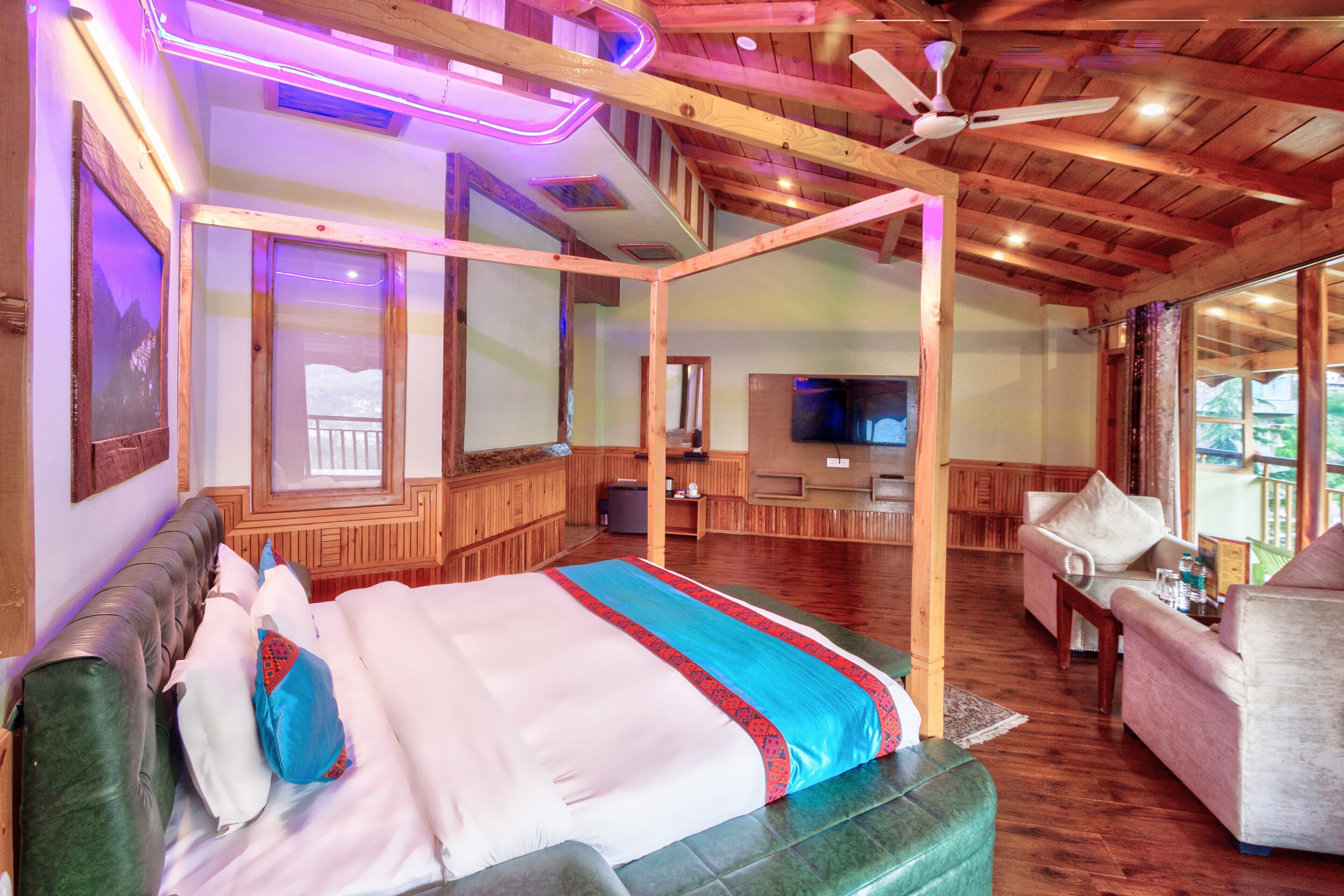 Ein geräumiger Raum mit einem großen Bett, Holzboden, Deckenventilator und Fernseher.