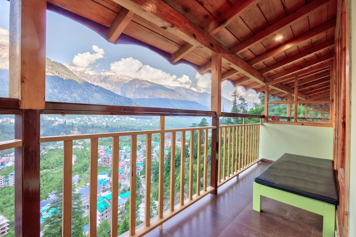 A balcony with a wooden railing overlooking a mountainous landscape.