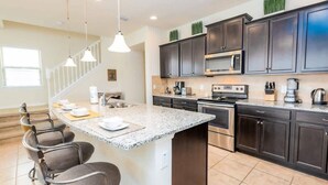 A modern kitchen with dark cabinets, a granite countertop, and stainless steel appliances. - Lakeview Resort Home, Private Pool, Gym, Game Room (Kissimmee)