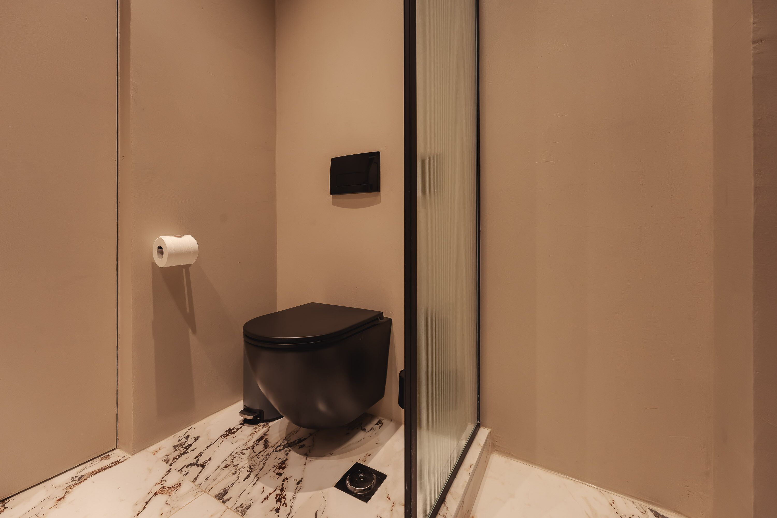 Une salle de bain moderne avec des toilettes, un espace douche et un sol en marbre.