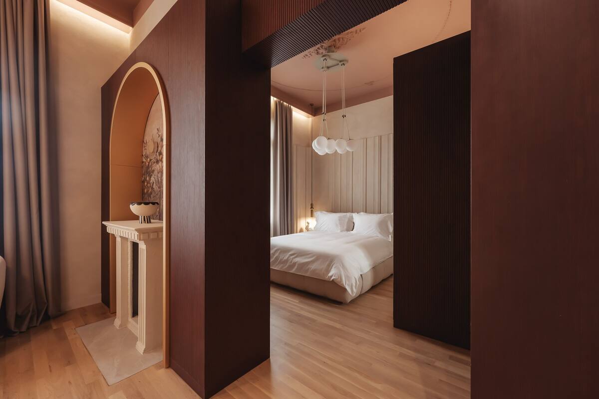 Un dormitorio moderno con una cama grande, un tocador con espejo y una lámpara colgante.