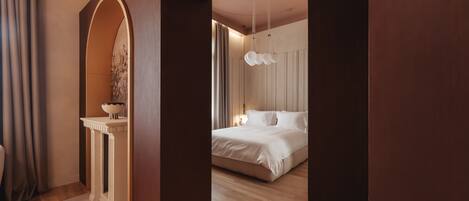 A modern bedroom with a large bed, a vanity with a mirror, and a hanging light fixture.