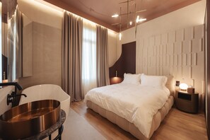 A modern bedroom with a large bed, a bathtub, and a nightstand with a lamp. - Zenith Premium Suites (Thessaloniki)