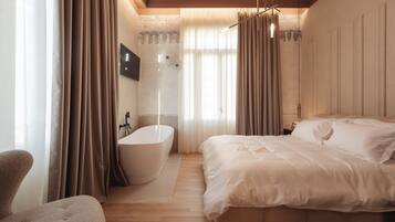 Un dormitorio moderno con una cama grande, una bañera y suelo de madera.