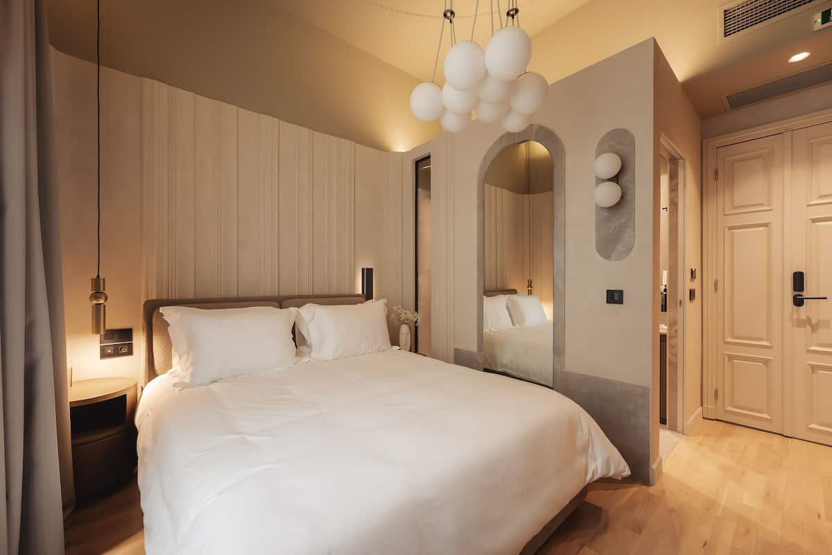 Un dormitorio moderno con una cama grande, una mesita de noche, un espejo y un armario.