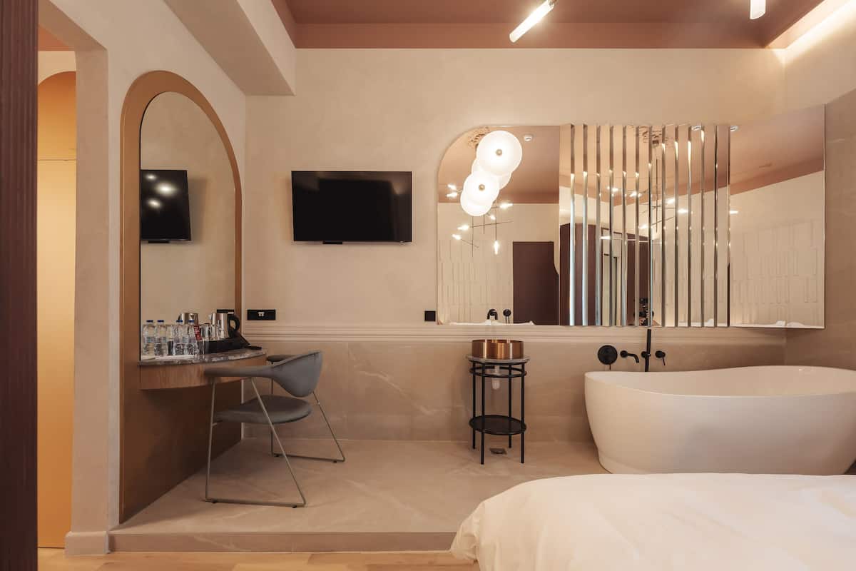 Un baño moderno con una bañera grande, un tocador con espejo y un televisor montado en la pared.