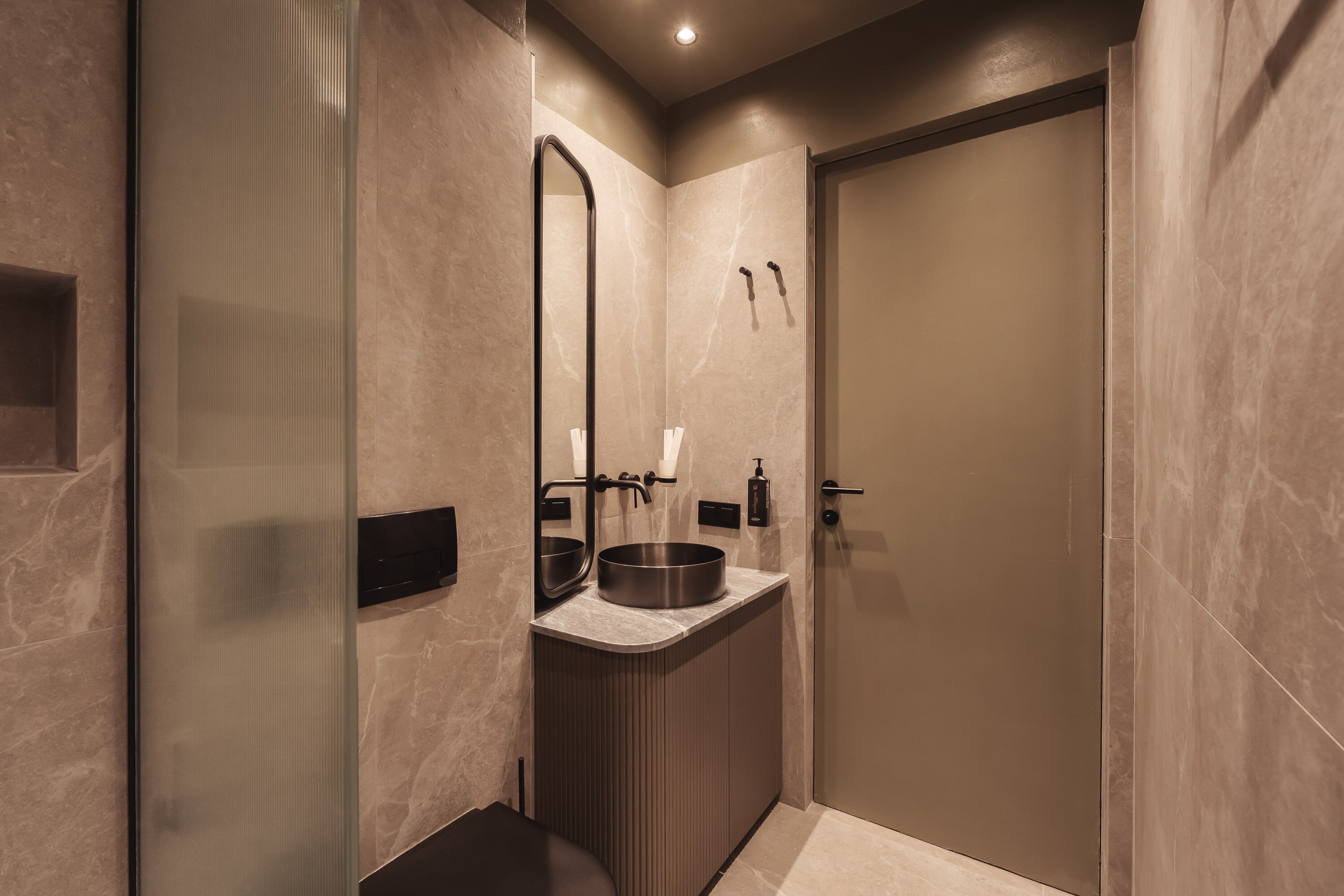 A modern bathroom with a large mirror, a sink with a basin, and a toilet.