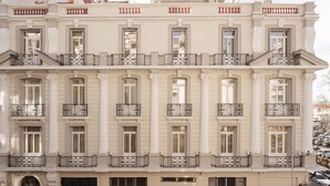 A multi-story building with a classical architectural style, featuring symmetrical windows, ornate balconies, and a central entrance.