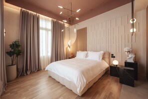 A modern bedroom with a large bed, a potted plant, and a marble nightstand with a bust. - Zenith Premium Suites (Thessaloniki)