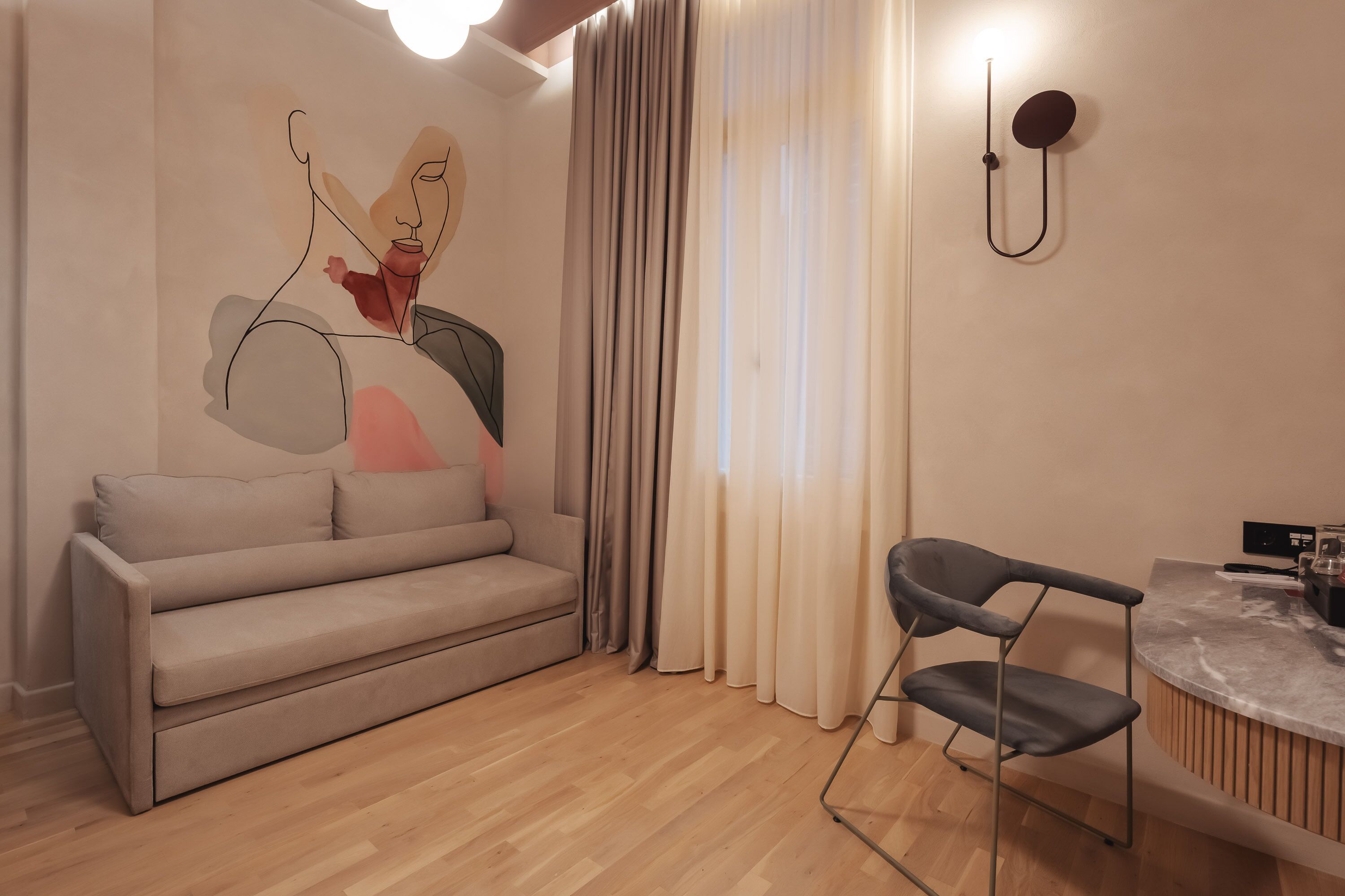 A modern living room with a sofa, a chair, a coffee table, and a wall-mounted light fixture.