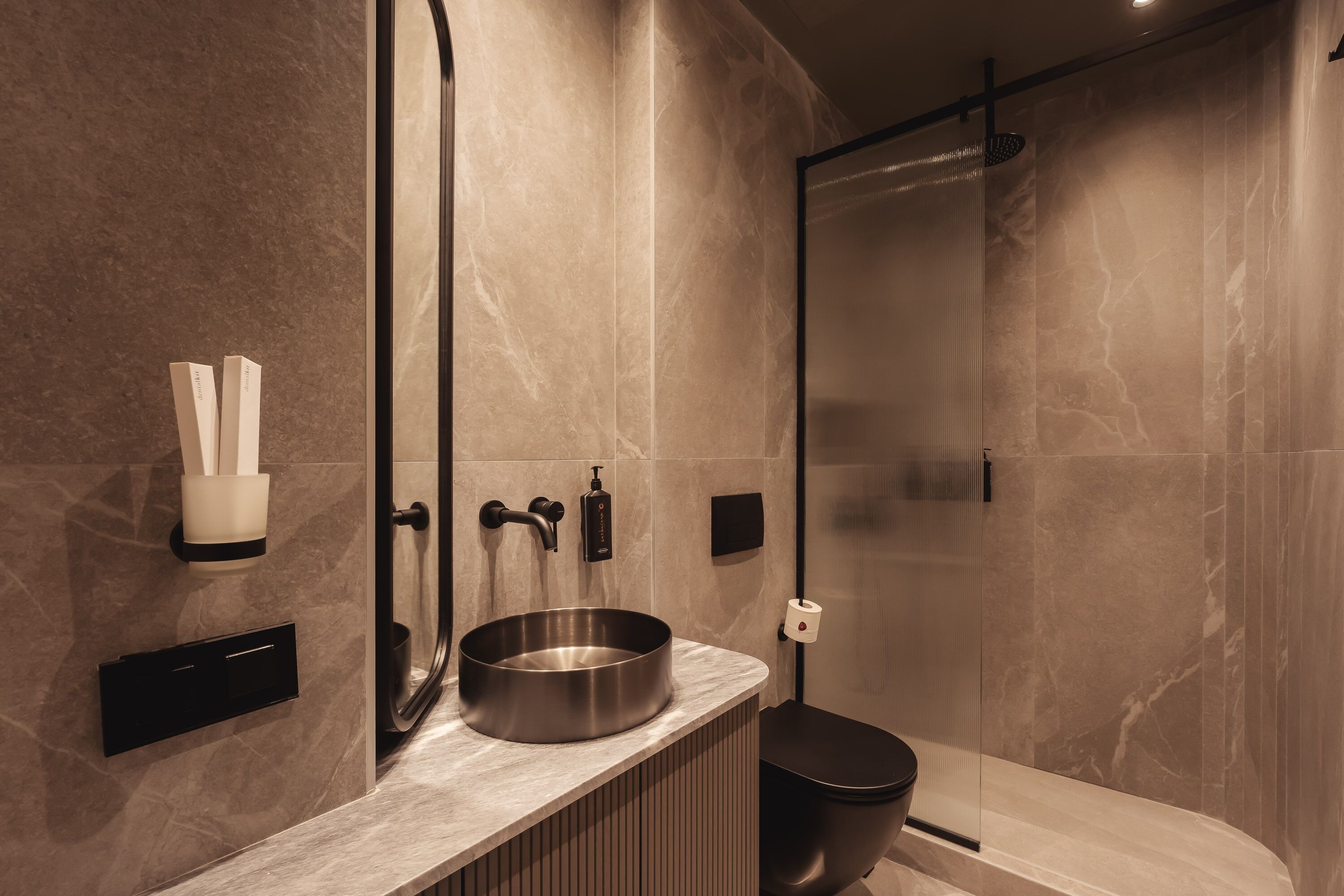 Une salle de bain moderne avec un lavabo en marbre, des toilettes et un espace douche.