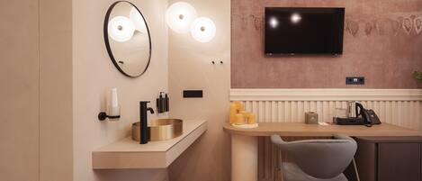 A modern hotel room with a vanity, a flat-screen TV, a desk with a chair, and a bed.