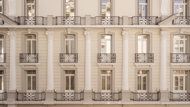 A multi-story building with symmetrical architecture, featuring evenly spaced windows, ornate balconies, and classical columns.