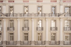 A multi-story building with symmetrical architecture, featuring evenly spaced windows, ornate balconies, and classical columns.