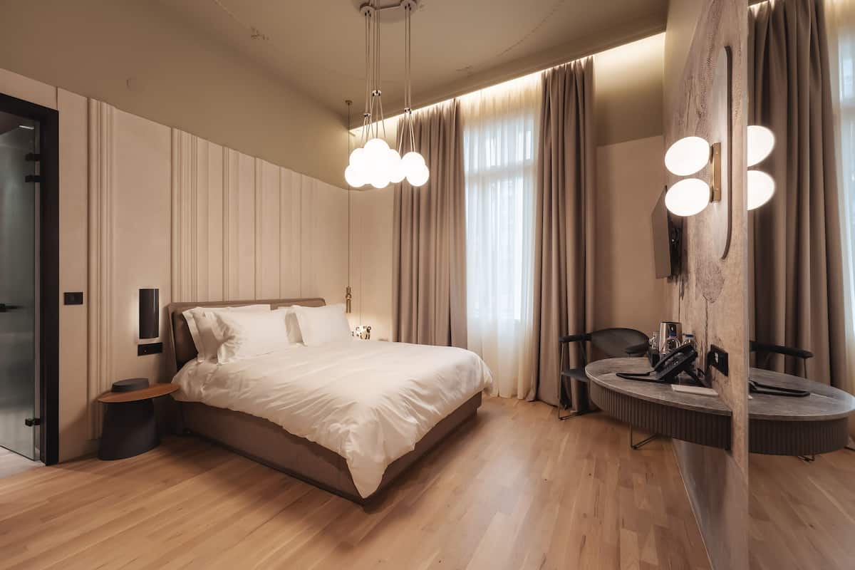 Un dormitorio moderno con una cama grande, mesitas de noche, un espejo redondo y un tocador empotrado con iluminación.