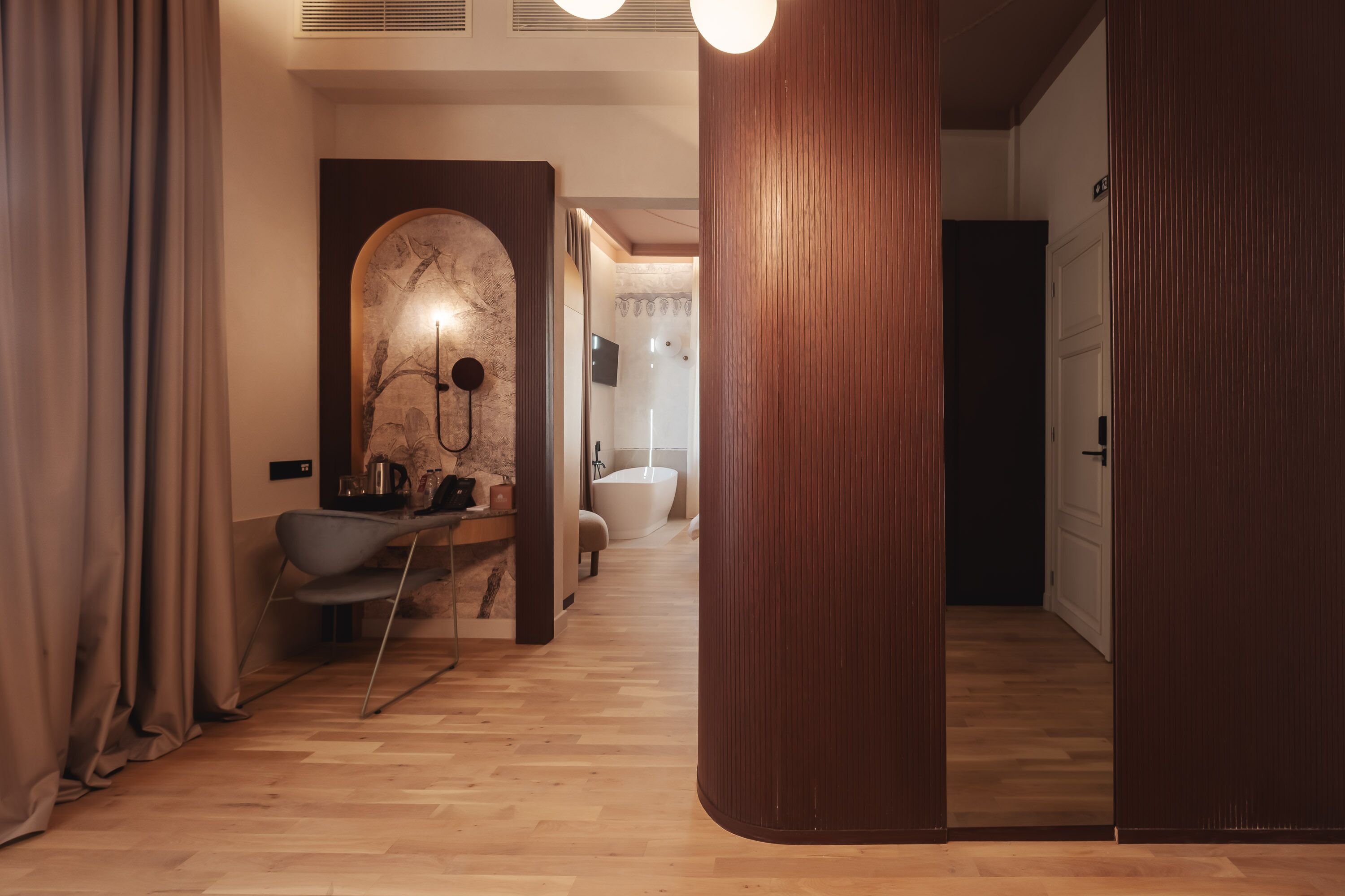 A modern bathroom with a marble sink, wooden floor, and a large mirror.