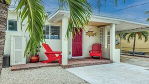 A house with a red door, two red chairs, and a potted plant. - Little Venice Family Affair 2 bedroom 1 bath One Block from the Ocean (Marathon)