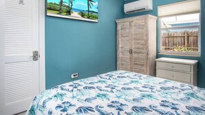 A bedroom with a bed, a wardrobe, an air conditioning unit, a ceiling fan, and a window with a view of palm trees. - Little Venice Family Affair 2 bedroom 1 bath One Block from the Ocean (Marathon)