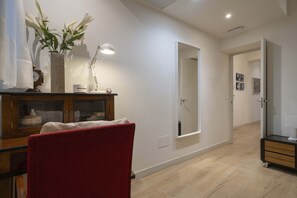 Ein modernes Interieur mit einem Holzkabinett, einem roten Sessel, einem Spiegel und einem Flur, der zu einer Tür führt.