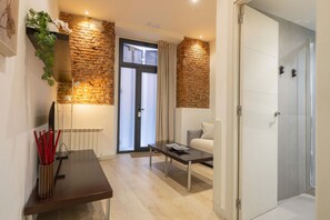 Ein modernes Wohnzimmer mit Backsteinwand, einer Couch, einem Couchtisch und einer Tür zu einem Badezimmer.