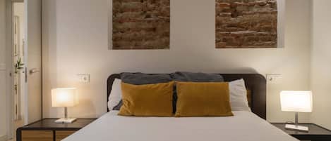 Une chambre d’hôtel avec un grand lit, deux lampes de chevet, une table de chevet et un mur orné de deux panneaux texturés.