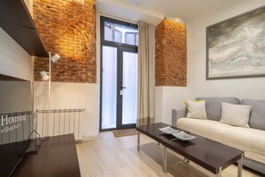 A modern living room with a brick accent wall, a sofa, a coffee table, and a door with frosted glass panels.