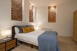 A bedroom with a bed, bedside tables, a lamp, and a radiator. - Housing Malasaña by Sharing Co (Madrid)