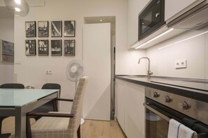 Eine kompakte Küche mit Mikrowelle, Backofen und Essbereich mit Tisch und Stühlen.