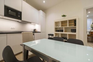 Eine moderne Küche mit Mikrowelle, Spüle und Essbereich inklusive Tisch und Stühlen.