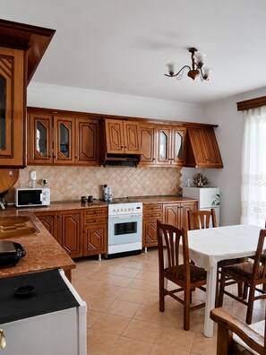 A kitchen with wooden cabinets, a stove, a microwave, and a dining area with chairs and a table.