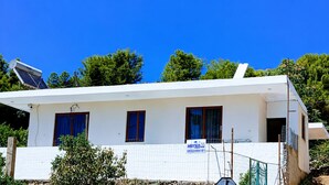 A white building with three windows, a solar panel, and a signboard. - Saranda 55  in Saranda, Albania. 10 min by Walking to City Center and Beach (Sarandë)