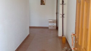 A narrow hallway with a wooden door on the right, a coat rack, and a small white cabinet in the distance. - Saranda 55  in Saranda, Albania. 10 min by Walking to City Center and Beach (Sarandë)