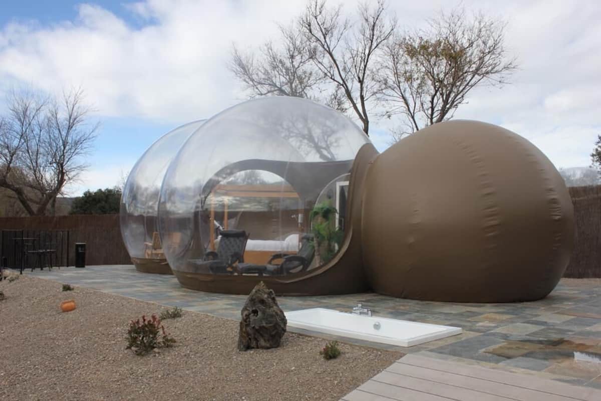 A transparent spherical structure with a seating area inside, a large brown sphere, and a small white table.