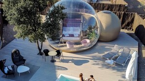 A modern outdoor pool area with a transparent dome structure, lounge chairs, and a small table. - Hotel Zielo de Levante (Tirig)