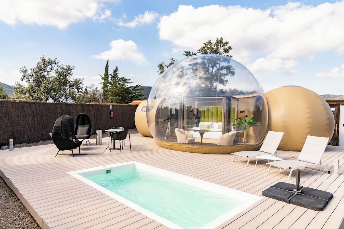 A transparent dome structure with a pool and lounge chairs.