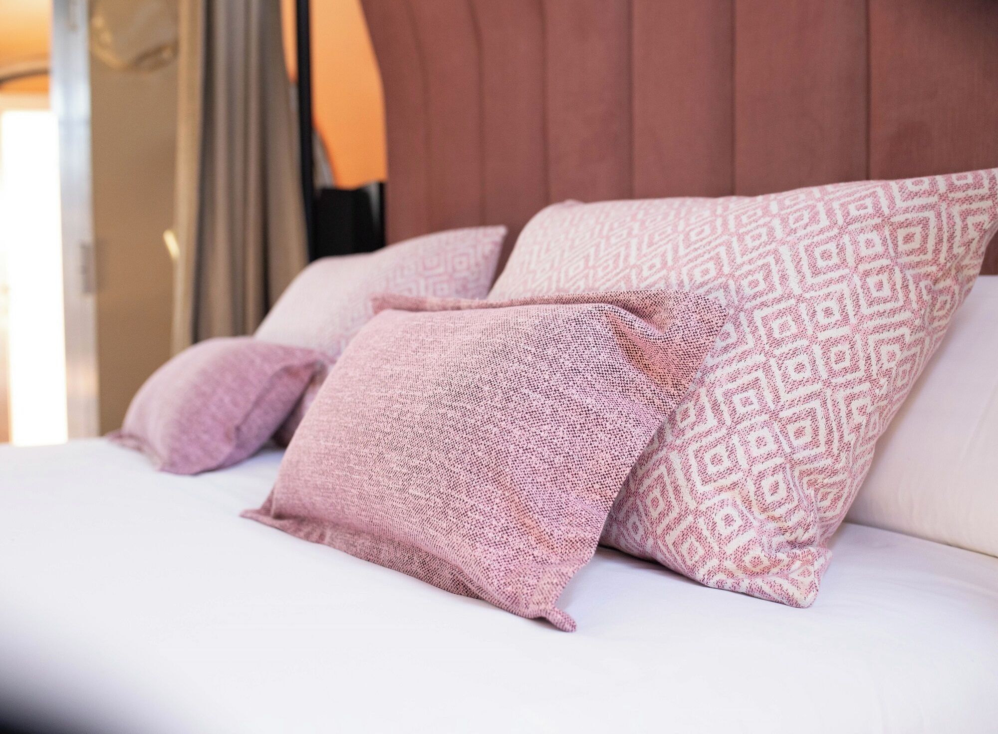 Una cama con almohadas estampadas y cabecera de madera.