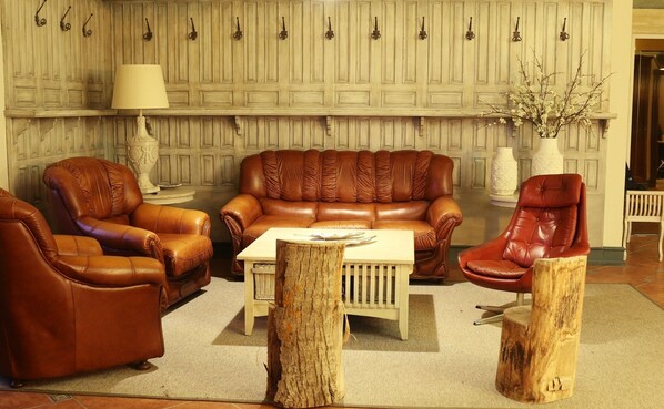 A living room with a brown leather sofa, two armchairs, a coffee table, and a lamp. - Hotel Zielo de Levante (Tirig)