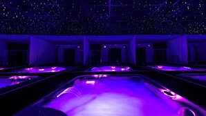 A room with multiple spa tubs under purple lighting, a starry ceiling, and a large mirror. - Hotel Zielo de Levante (Tirig)