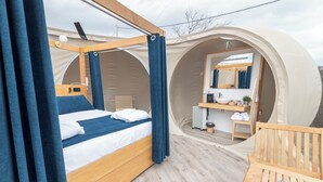 A cozy, circular tent-style room with a wooden bed, a small table, and a chair. - Hotel Zielo de Levante (Tirig)