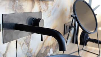 Un baño con un grifo moderno, un espejo y una pared de mármol.