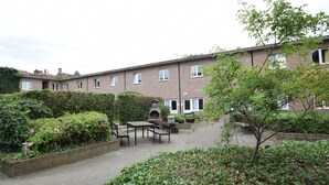 A courtyard with a brick building, a barbecue area, and a wheelbarrow.
