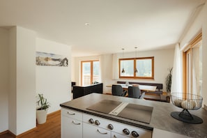 Una cocina moderna con una isla central, armarios de madera y un comedor con un banco y sillas.