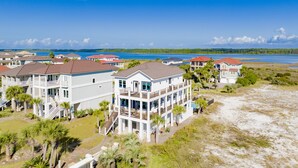A coastal residential area with multi-story houses featuring balconies, a beach, and a view of the ocean. - Luxury Coastal Retreat | Heated Private Pool | Resort Style Amenities (Gulf Shores)