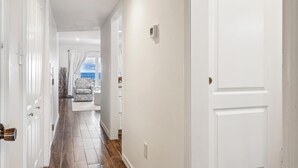Ein Flur mit weißen Wänden und Holzboden, der zu einem Zimmer mit Meerblick führt.