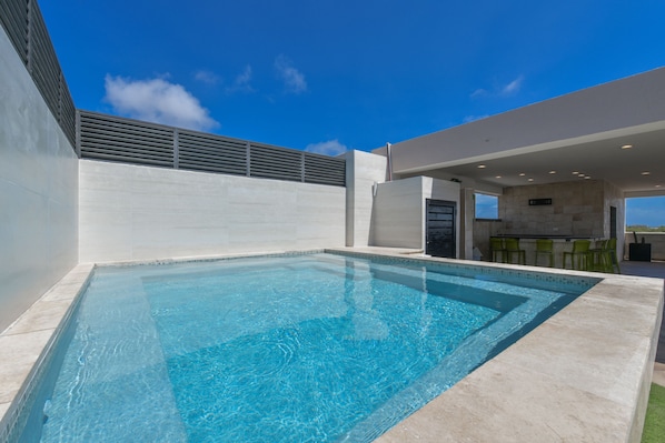 A modern outdoor swimming pool with a clear blue sky above.